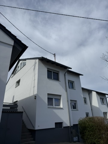 Moderner Wohnkomplex mit mehreren weißen Gebäuden unter einem bewölkten Himmel, seitliche Sicht mit Treppe im Vordergrund