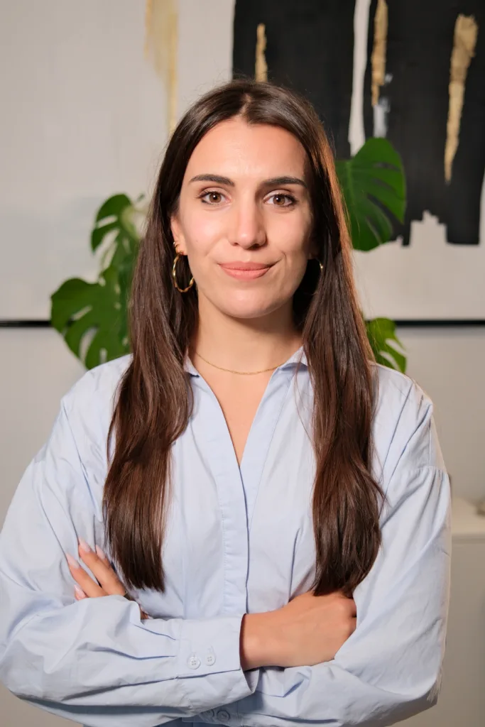 Sonja Gerst, Ansprechpartnerin bei BetonGold Immobilien, steht mit verschränkten Armen vor einer modernen Büroumgebung
