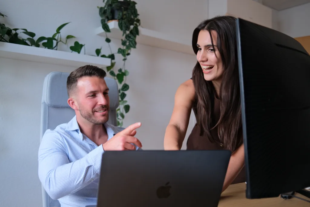 Mike Grammel und Sonja Gerst erläutern investitionsmöglichkeiten in Kapitalanlage-Immobilien am Laptop in einer profession...